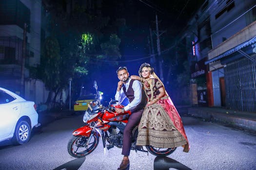 A stylish bride and groom pose on a motorcycle during their nighttime wedding photo shoot in Dhaka, Bangladesh.